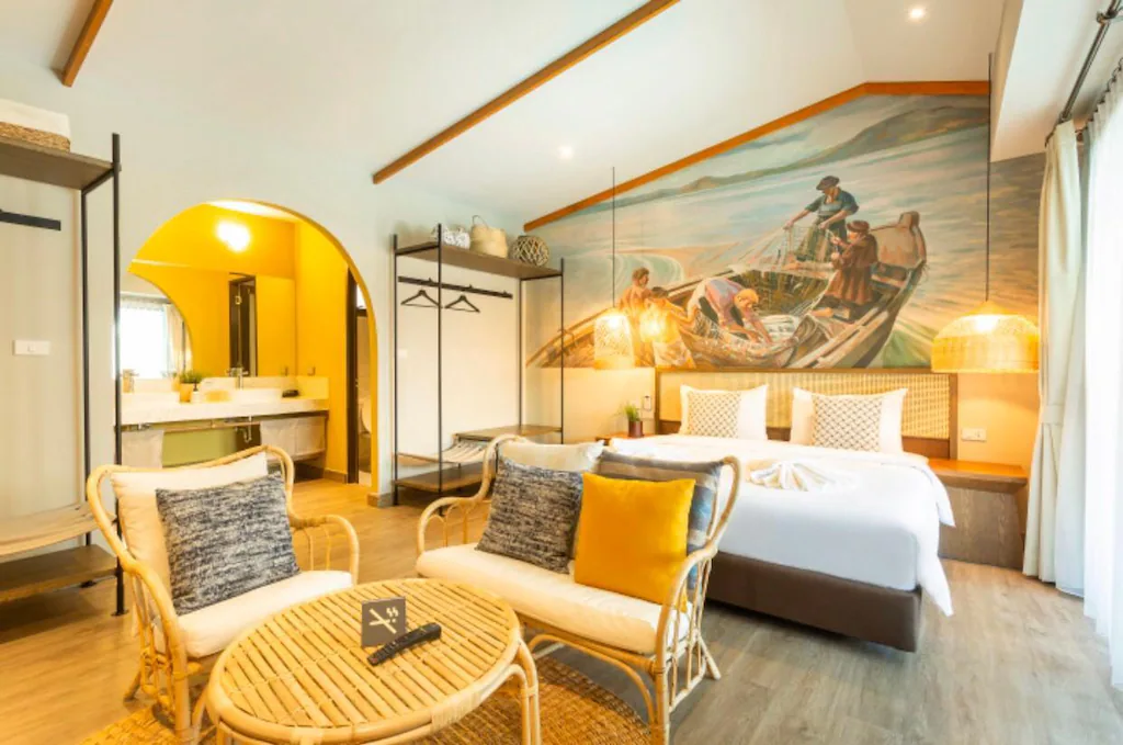 ห้องพักในโรงแรมทันสมัยที่มีเตียงขนาดใหญ่ เก้าอี้และโต๊ะหวาย ตู้ ที่พักสตูลแนวธรรมชาติ เสื้อผ้าแบบเปิด และภาพจิตรกรรมฝาผนังรูปคนบนเรือเหนือเตียง ถือเป็นการพักผ่อนแนวธรรมชาติในอุดมคติสำหรับการพักผ่อนที่ได้รับแรงบันดาลใจจากธรรมชาติ.