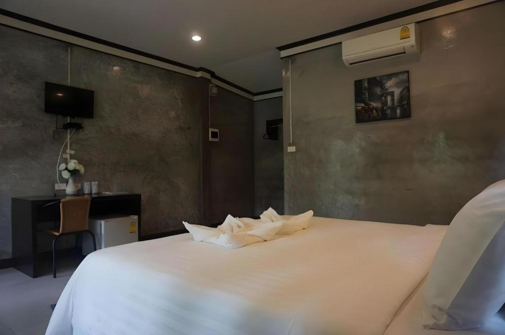 ห้องพักในโรงแรมที่มีเตียงขนาดใหญ่ โต๊ะพร้อมเก้าอี้ ทีวีติดผนัง เครื่องปรับอากาศ และผนังสีเทา มอบความสะดวกสบายในสไตล์สตูลแนว ที่พักสตูลแนวธรรมชาติ ธรรมชาติ การจัดวางผ้าเช็ดตัวไว้บนเตียงอย่างพิถีพิถัน.