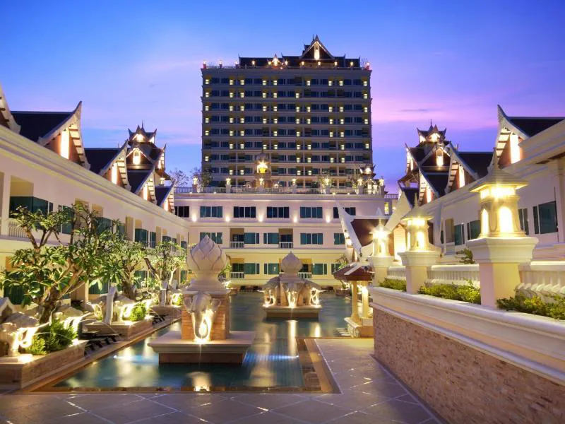 โรงแรมขนาดใหญ่ที่มีองค์ประกอบสถาปัตยกรรมไทยแบบดั้งเดิม หนึ่งในตัวเลือกที่พักชะอำที่โดดเด่น ล้อมรอบด้วยสระว่ายน้ำในลานกลางแจ้งและส่องสว่างในยามค่ำคืนภายใต้ท้องฟ้าสีม่วง.