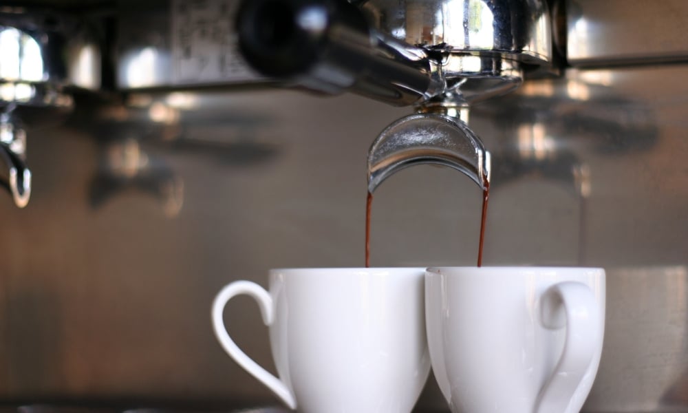 ถ้วยเซรามิกสีขาวสองใบถูกวางไว้ใต้เครื่องชงกาแฟเอสเปรสโซ โดย ที่เที่ยวเลย กาแฟถูกเทลงในถ้วยทั้งสองใบพร้อมกัน—เหมาะอย่างยิ่งสำหรับการเติมพลังก่อนที่คุณจะออกไปสำรวจ ที่เที่ยวเลย.