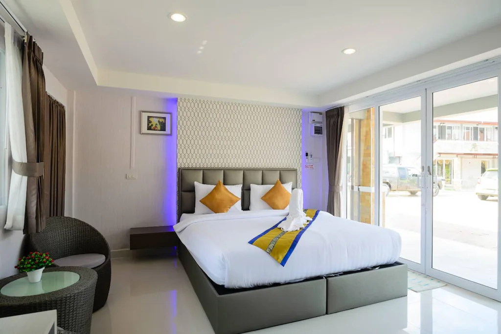 ห้องพักในโรงแรมทันสมัยพร้อมเตียงคู่ เก้าอี้สีน้ำตาล 2 ตัว โต๊ะเล็กพร้อมต้นไม้ หน้าต่างบานใหญ่ หมอนประดับ ที่พักสตูลแนวธรรมชาติ และผ้าเช็ดตัวบนเตียง เหมาะสำหรับผู้ที่กำลังมองหาการพักผ่อนแนวธรรมชาติในการพักผ่อน.