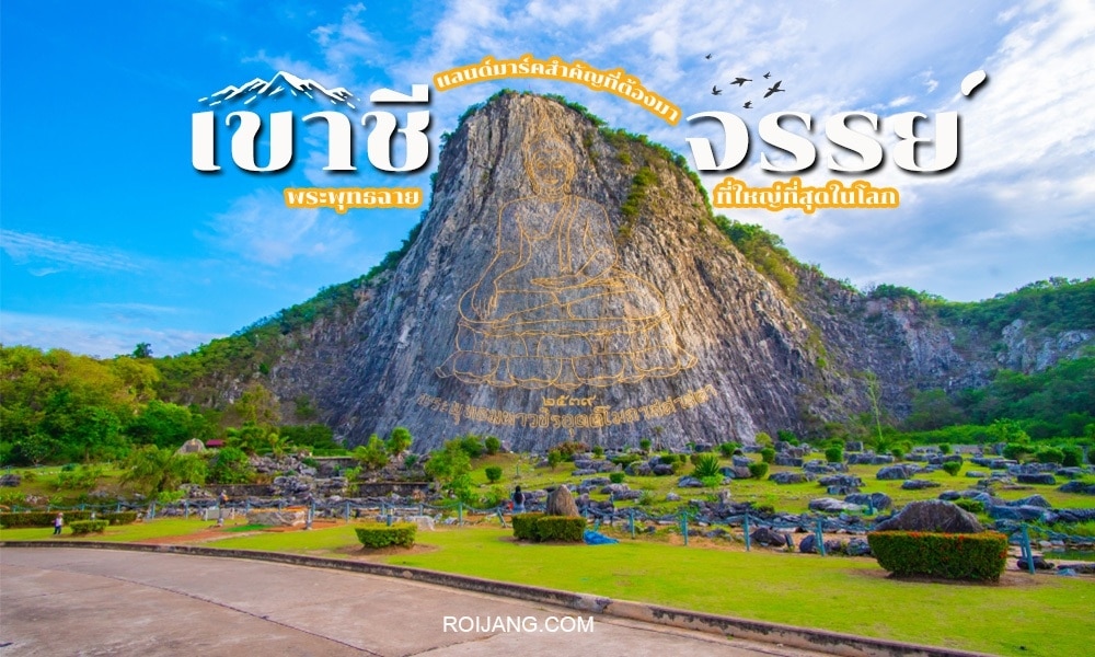 ภูเขาหินปูนขนาดใหญ่ที่มีพระพุทธรูปสีทองสลักอยู่รายล้อมด้วยต้นไม้เขียวขจีและโขดหินใต้ท้องฟ้าสีฟ้าใส เป็นสถานที่ที่ต้องมาชมสำหรับผู้ที่ต้องการ ที่เที่ยวสัตหีบ มีข้อความภาษาไทยทับอยู่ด้านบนของภาพ.