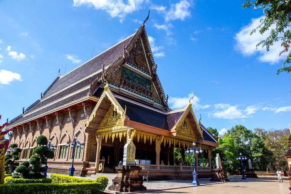วัดพุทธไทยขนาดใหญ่ที่ประดับ ที่เที่ยวเลย ประดาอย่างวิจิตร มีหลังคาแหลม ตกแต่งด้วยทองคำ และรายละเอียดที่ประณีต ล้อมรอบด้วยต้นไม้และท้องฟ้าสีฟ้าใส—เป็นหนึ่งในสถานที่ท่องเที่ยวที่ต้องไปเยือนเมื่อมาจังหวัดเลย.