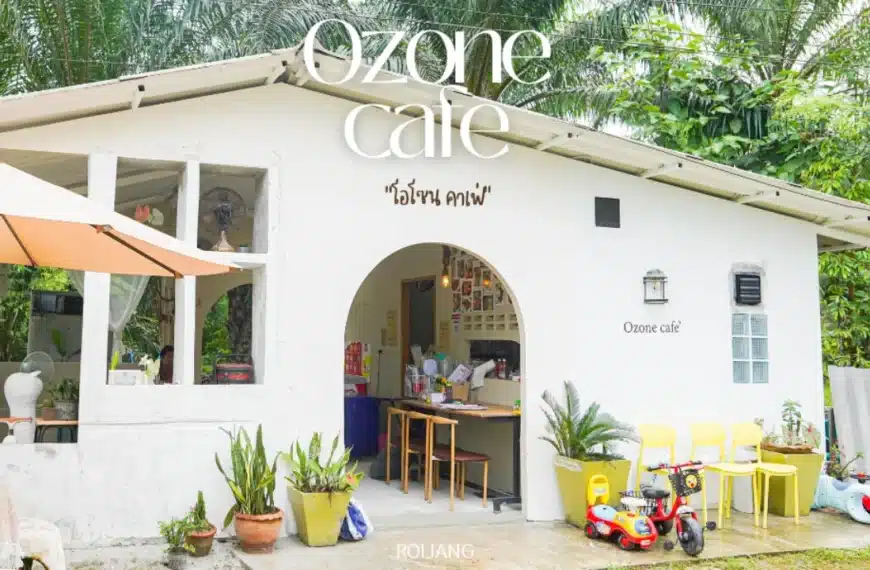 อาคารสีขาวขนาดเล็กที่มีป้ายเขียนว่า "โอโซนคาเฟ่" พร้อมเก้าอี้สีเหลือง ต้นไม้ในกระถาง และของเล่นเด็กอยู่ด้านนอก ล้อมรอบด้วยพืชพรรณสีเขียว เป็น สถานีดีจัง ที่น่าเชิญชวนสำหรับครอบครัว.