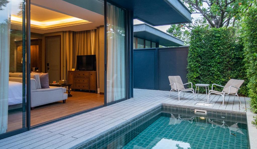 ห้องพักโรงแรมสมัยใหม่พร้อมประตูบานเลื่อนเปิดโล่งนำไปสู่ลานส่วนตัวที่มีสระว่ายน้ำขนาดเล็ก เก้าอี้อาบแดดสองตัว และโต๊ะท่ามกลางธรรมชาติสีเขียว—เหมาะสำหรับผู้ที่มองหา ที่พักเขาใหญ่ ในบรรยากาศเงียบสงบ.