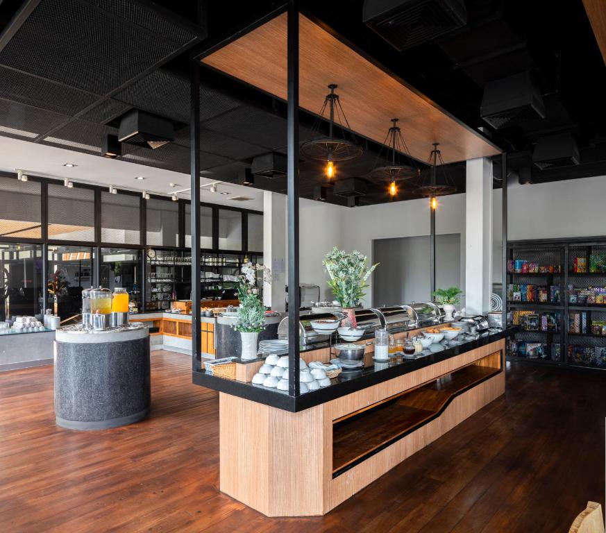 ร้านอาหารบุฟเฟ่ต์สมัยใหม่พร้อมพื้นไม้ สถานีอาหารกลางแจ้ง พืชประดับ และชั้นวางของตามผนังด้านหลัง—เหมาะสำหรับผู้ที่กำลังสำรวจ ที่เที่ยวสระแก้ว หรือค้นหาประสบการณ์ สระแก้วที่เที่ยว.