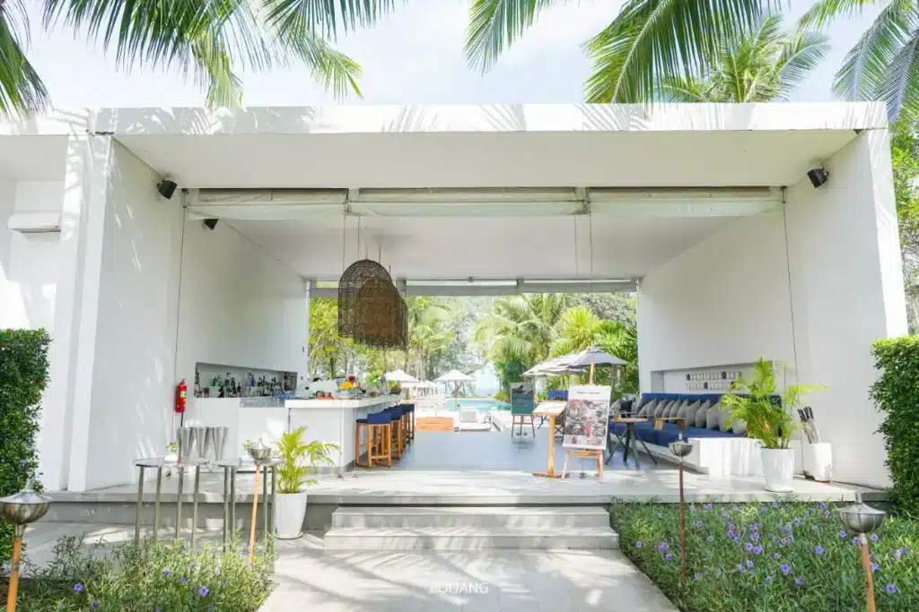 บาร์ทันสมัยแบบเปิดโล่งที่ Meliá Phuket พร้อมผนังสีขาว โคมไฟหวาย พื้นที่นั่งสบาย และวิวสระว่ายน้ำที่ล้อมรอบด้วยต้นปาล์ม—เหมาะอย่างยิ่งสำหรับการเพลิดเพลินกับ Soul of Saturday Brunch.