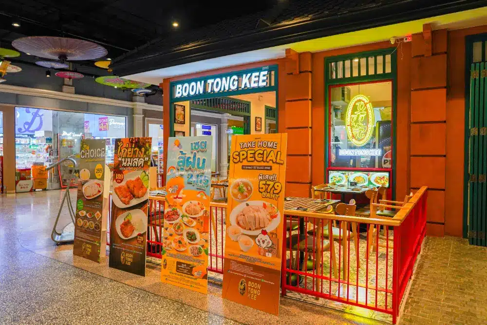 ภายนอกของร้าน Boon Tong Kee, ร้านอาหารในเซ็นทรัลภูเก็ต, พร้อมป้ายเมนูสีสันสดใสและอาหารพิเศษที่จัดแสดงใกล้ทางเข้าภายในห้างสรรพสินค้า.