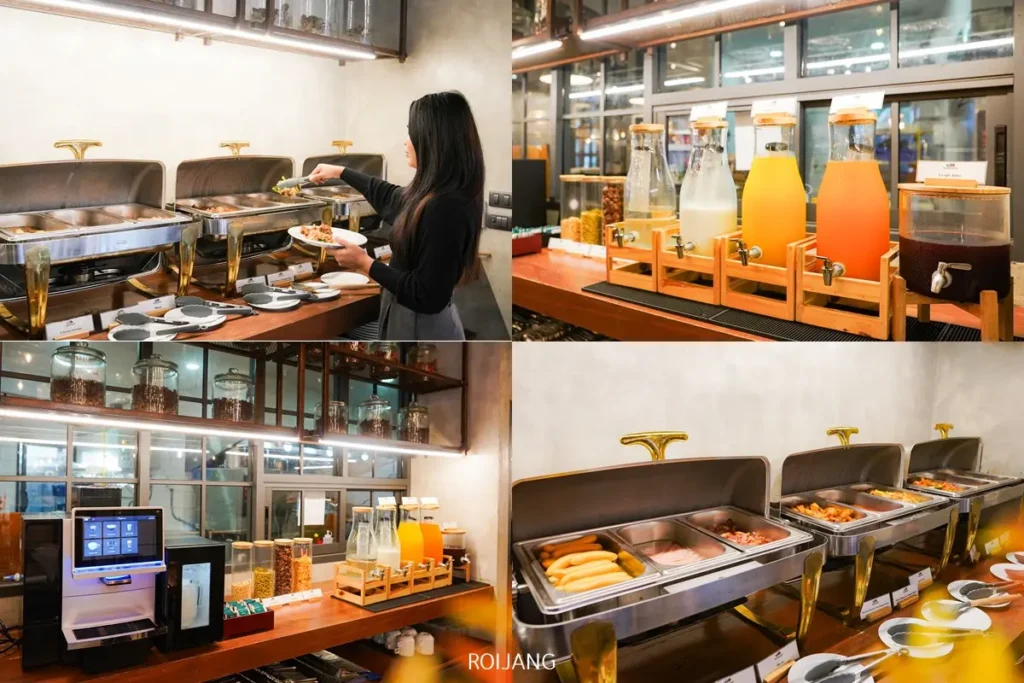 ผู้หญิงคนหนึ่งเสิร์ฟอาหารที่ Kokotel ภูเก็ตในยาง พร้อมถาดอาหารแบบอุ่น, เครื่องจ่ายเครื่องดื่มที่เต็มไปด้วยน้ำผลไม้และน้ำเปล่า, เครื่องชงกาแฟ, และอาหารหลากหลายชนิดที่น่ารับประทานจัดแสดงอยู่.