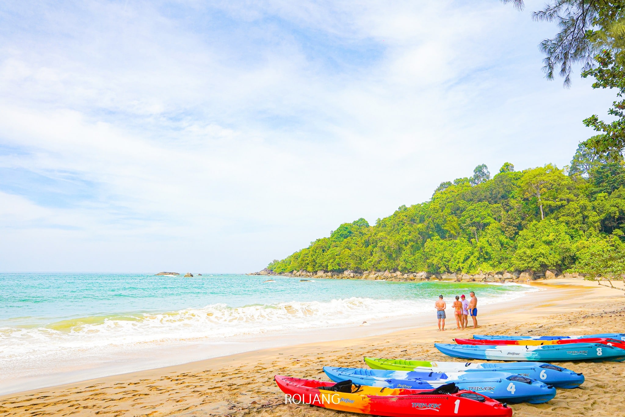 ชายหาดทรายที่มีเรือคายัคสีสันสดใสเรียงรายอยู่ริมฝั่ง กลุ่มคนยืนอยู่ใกล้ๆ และต้นไม้สีเขียวขนาบชายฝั่งใต้ท้องฟ้าที่มีเมฆบางส่วน—เหมาะสำหรับการสำรวจ ที่เที่ยวตะกั่วป่า .