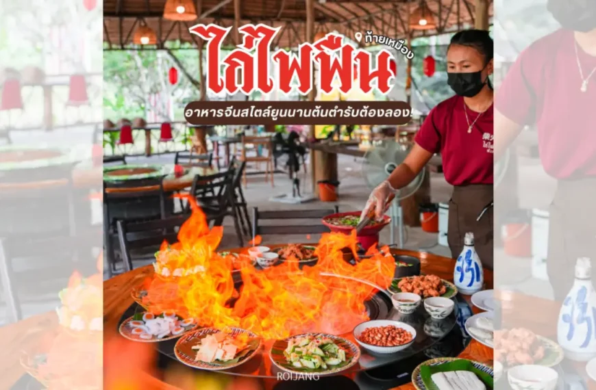 พนักงานร้านอาหารสวมหน้ากากกำลังเสิร์ฟอาหารบนโต๊ะที่มีเปลวไฟลุกโชนจากจานไก่ไฟฟืน มีอาหารไทยหลากหลายชนิดจัดแสดงอยู่ และลูกค้าต่างนั่งรับประทานอาหารอยู่ด้านหลัง.