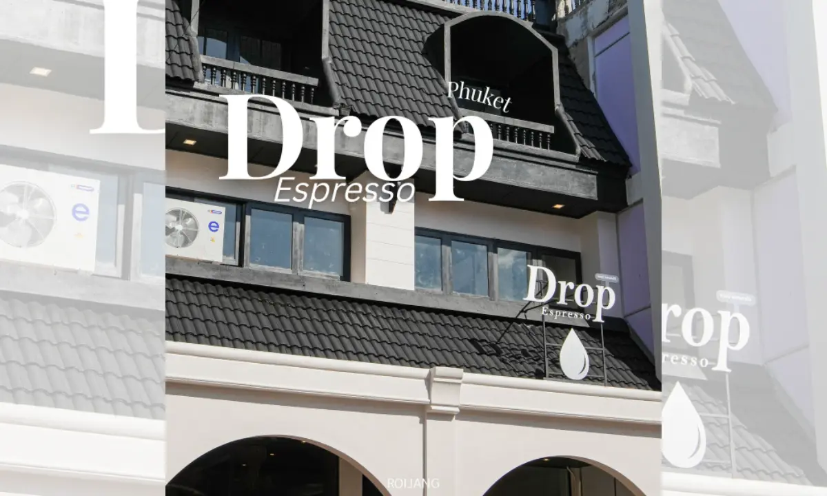 ภายนอกของอาคารที่มีหลังคากระเบื้องสีดำและระเบียง มีป้าย "Drop Espresso Phuket" ติดอยู่ใกล้กับเครื่องปรับอากาศสองเครื่อง ให้บรรยากาศที่มีสไตล์คล้ายกับ
