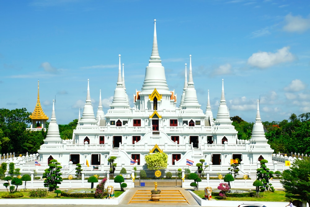 วัดขาวที่มียอดแหลมหลายยอดและประดับด้วยสีทอง ตั้งอยู่ท่ามกลางธรรมชาติสีเขียวและธงที่โบกสะบัดใต้ท้องฟ้าสีคราม—เป็นสถานที่ที่ไม่ควรพลาดสำหรับผู้ที่มาเยือนบางปูที่เที่ยว.