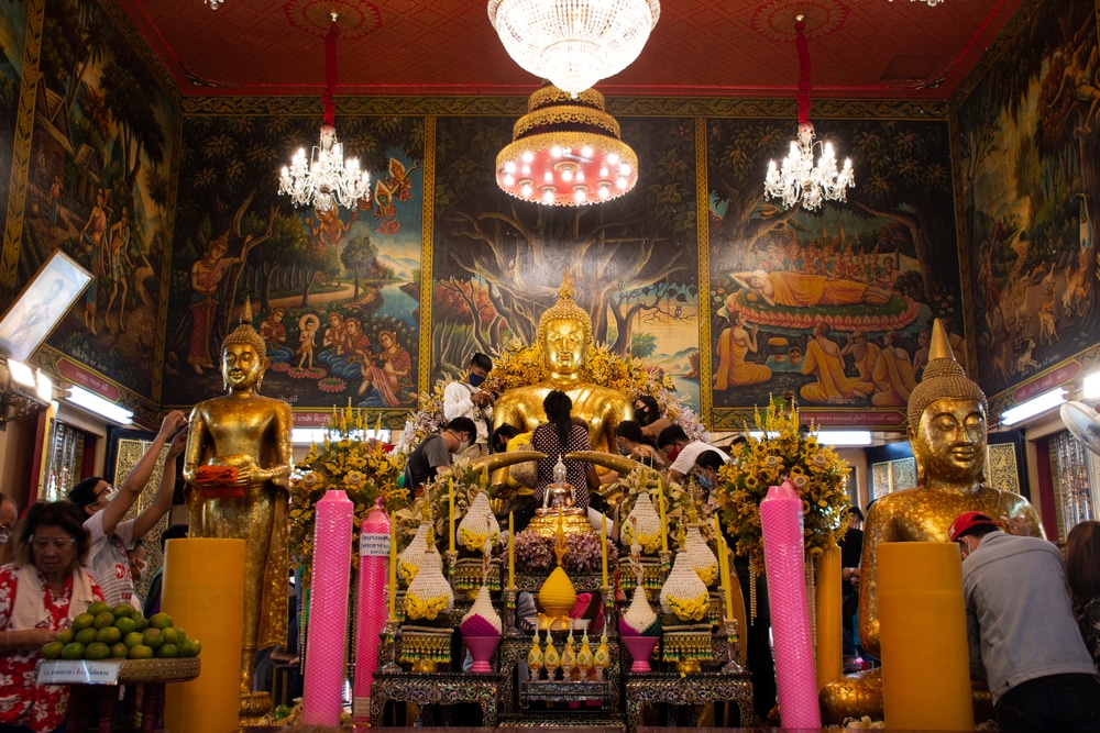 ผู้คนนำแผ่นทองคำเปลวมาปิดและถวายเครื่องบูชาต่อพระพุทธรูปภายในวัดที่ตกแต่งอย่างหรูหรา มีโคมไฟระย้า ดอกไม้ และเทียนสีชมพูขนาดใหญ่—เป็นประสบการณ์อันสงบเงียบที่เพิ่มคุณค่าให้กับทุกการเดินทางท่องเที่ยวบางปู.