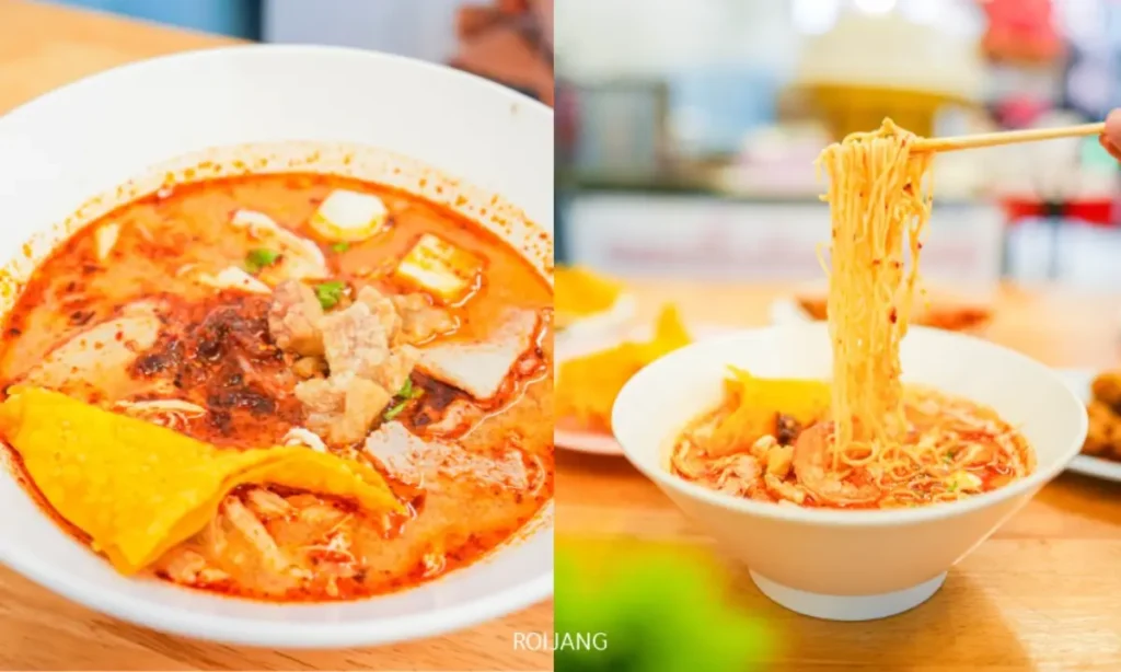 ชามบะหมี่น้ำซุปเผ็ดพร้อมเครื่องเคียงหลากหลาย; ทางด้านขวา ตะเกียบกำลังคีบเส้นบะหมี่จากชาม พร้อมกับของว่างอบกรอบที่วางอยู่ข้างๆ.