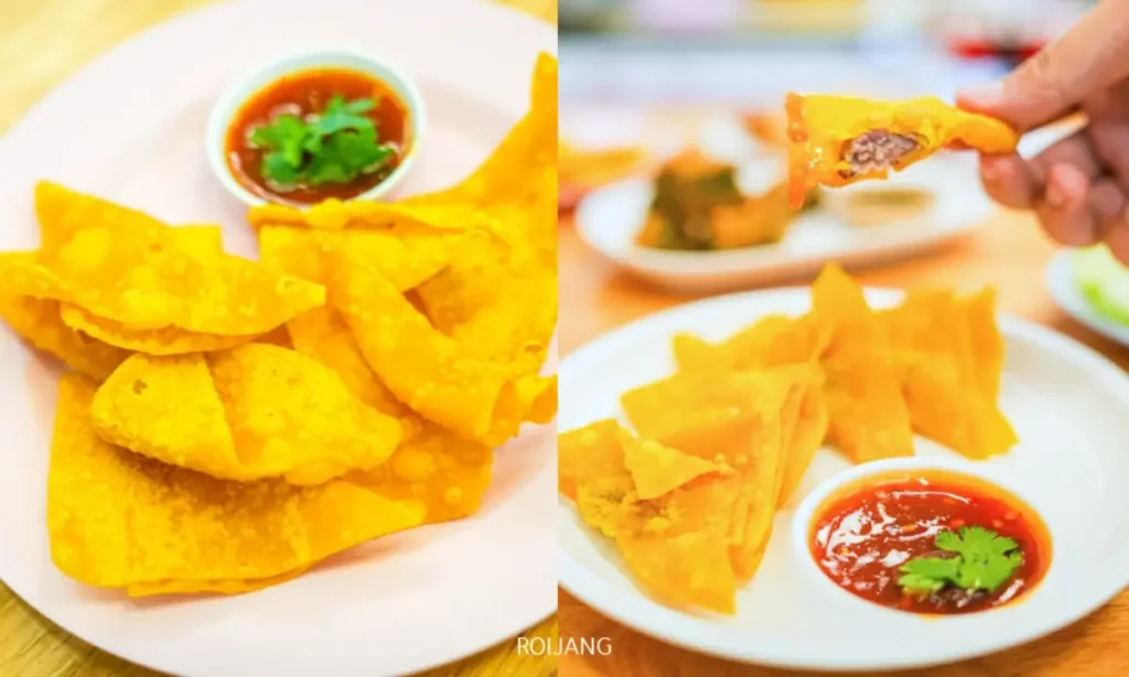 สองจานของเกี๊ยวทอดกรอบจาก ก๋วยเตี๋ยว นิวเบรคแตก เสิร์ฟพร้อมชามน้ำจิ้มสีแดงและผักชีตกแต่ง; มือข้างหนึ่งถือเกี๊ยวที่ถูกกัดไปแล้วอยู่ทางขวา.