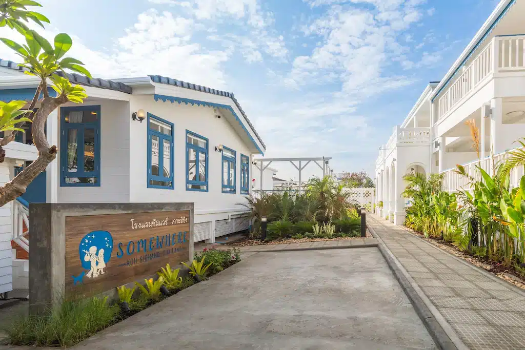 อาคารสีขาวพร้อมขอบสีน้ำเงินและรวม ที่เที่ยวเกาะสีชัง เกาะสวยๆ ในที่เที่ยวชลบุรี ไป เที่ยวเกาะสีชัง เดินทางง่ายๆ ใกล้กรุงเทพแบบไปเช้าเย็นกลับได้ หลีกหนีความวุ่นวาย พร้อมอวดสถานที่สโลว์ไลฟ์
ป้ายไม้ที่เขียนว่า "บางสิ่ง" ตั้งอยู่ข้างทางเดินปูด้วยหินล้อมรอบด้วยต้นไม้เขตร้อนภายใต้ท้องฟ้าที่มีเมฆบางส่วน ถ่ายทอดเสน่ห์ของ ที่เที่ยวเกาะสีชัง สำหรับผู้ที่ต้องการ เที่ยวเกาะสีชัง.