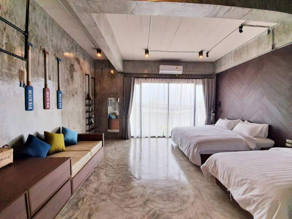 ห้องพักโรงแรมสมัยใหม่พร้อมเตียงคู่สองเตียง โซฟาที่แสนสบายพร้อมรวม ที่เที่ยวเกาะสีชัง เกาะสวยๆ ในที่เที่ยวชลบุรี ไป เที่ยวเกาะสีชัง เดินทางง่ายๆ ใกล้กรุงเทพแบบไปเช้าเย็นกลับได้ หลีกหนีความวุ่นวาย พร้อมอวดสถานที่สโลว์ไลฟ์
หมอนสีสันสดใส ผนังและพื้นคอนกรีต หน้าต่างบานใหญ่พร้อมผ้าม่านบาง และไฟเพดาน—เหมาะสำหรับการพักผ่อนหลังจากวันท่องเที่ยวเกาะสีชัง.