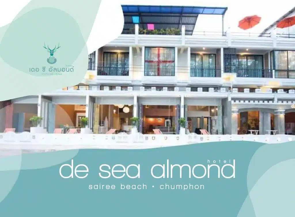 มุมมองด้านหน้าของโรงแรม De Sea Almond ใน ชุมพรที่เที่ยว มีระเบียง เที่ยวชุมพร หน้าต่างบานใหญ่ และบริเวณสระว่ายน้ำพร้อมเก้าอี้อาบแดด; มีป้ายชื่อและรายละเอียดสถานที่ทับซ้อนอยู่.