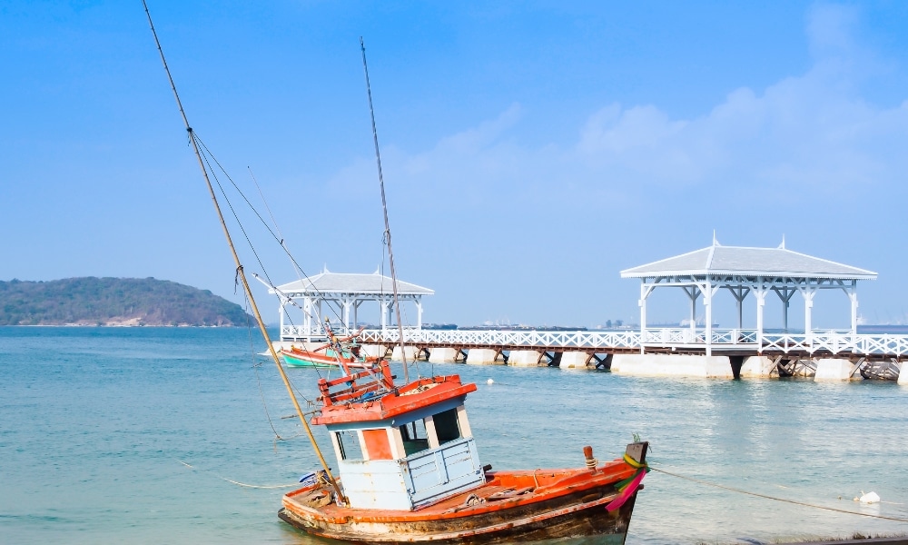 เรือประมงลำเล็กที่ผ่านการใช้งานและกัดกร่อนตามกาลเวลาจอดรวม ที่เที่ยวเกาะสีชัง เกาะสวยๆ ในที่เที่ยวชลบุรี ไป เที่ยวเกาะสีชัง เดินทางง่ายๆ ใกล้กรุงเทพแบบไปเช้าเย็นกลับได้ หลีกหนีความวุ่นวาย พร้อมอวดสถานที่สโลว์ไลฟ์
ทอดสมออยู่ใกล้ชายฝั่ง ใกล้กับท่าเทียบเรือไม้สีขาวและศาลากลางน้ำที่ทอดยาวออกไปในทะเลสีฟ้าสงบ เหมาะอย่างยิ่งสำหรับผู้ที่ต้องการเที่ยวเกาะสีชังใต้ท้องฟ้าแจ่มใส พร้อมชมเกาะที่อยู่ไกลลิบตา.