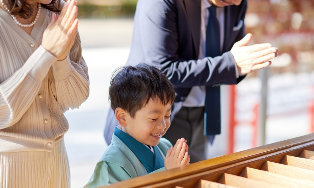 เด็กในชุดประจำถิ่นยิ้มและภาวนาอยู่ข้างผู้ใหญ่สองคนที่พนมมือไว้ที่แท่นบูชาไม้ในบรรยากาศกลางแจ้งที่สว่างไสว รวม ที่เที่ยวเกาะสีชัง เกาะสวยๆ ในที่เที่ยวชลบุรี ไป เที่ยวเกาะสีชัง เดินทางง่ายๆ ใกล้กรุงเทพแบบไปเช้าเย็นกลับได้ หลีกหนีความวุ่นวาย พร้อมอวดสถานที่สโลว์ไลฟ์
สะท้อนจิตวิญญาณอันสงบของ ที่เที่ยวเกาะสีชัง.