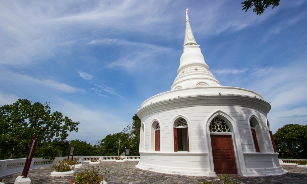 เจดีย์สีขาวทรงกลม มีหน้าต่างโค้งรวม ที่เที่ยวเกาะสีชัง เกาะสวยๆ ในที่เที่ยวชลบุรี ไป เที่ยวเกาะสีชัง เดินทางง่ายๆ ใกล้กรุงเทพแบบไปเช้าเย็นกลับได้ หลีกหนีความวุ่นวาย พร้อมอวดสถานที่สโลว์ไลฟ์
และยอดแหลมสูง ตั้งอยู่บนพื้นที่ปูด้วยหินล้อมรอบด้วยพืชพรรณสีเขียวภายใต้ท้องฟ้าที่มีเมฆบางส่วน—หนึ่งในไฮไลท์สำหรับผู้ที่มองหาสถานที่ท่องเที่ยวเกาะสีชัง.