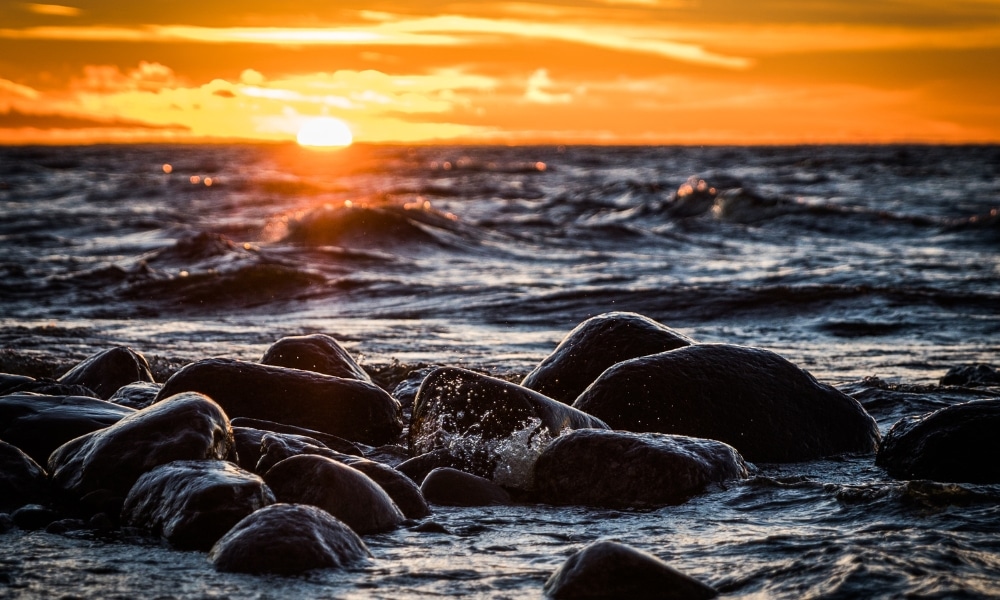 คลื่นซัดกระทบโขดหินสีดำในเบื้องหน้า ขณะที่พระอาทิตย์กำลังลับขอบฟ้าเหนือเกาะสีชัง แผ่ประกายแสงสีส้มเจิดจ้าไปรวม ที่เที่ยวเกาะสีชัง เกาะสวยๆ ในที่เที่ยวชลบุรี ไป เที่ยวเกาะสีชัง เดินทางง่ายๆ ใกล้กรุงเทพแบบไปเช้าเย็นกลับได้ หลีกหนีความวุ่นวาย พร้อมอวดสถานที่สโลว์ไลฟ์
ทั่วท้องฟ้าและผืนน้ำ.