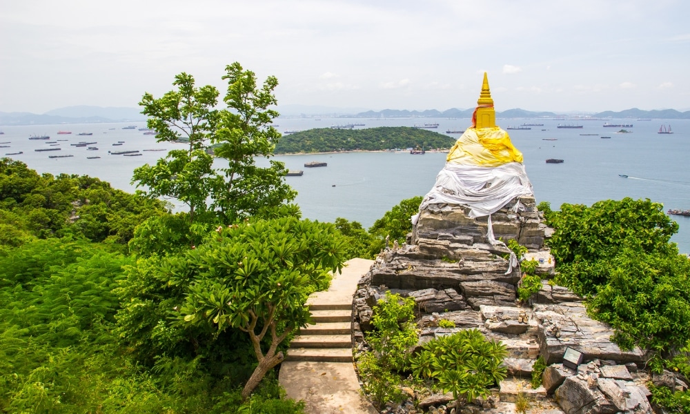 เจดีย์ทองคำห่อหุ้มด้วยผ้าขาวตั้งอยู่รวม ที่เที่ยวเกาะสีชัง เกาะสวยๆ ในที่เที่ยวชลบุรี ไป เที่ยวเกาะสีชัง เดินทางง่ายๆ ใกล้กรุงเทพแบบไปเช้าเย็นกลับได้ หลีกหนีความวุ่นวาย พร้อมอวดสถานที่สโลว์ไลฟ์
บนยอดเขาหินที่มองเห็นทะเล มีเรือและเกาะต่างๆ ปรากฏอยู่เบื้องหลัง—เหมาะสำหรับผู้ที่มองหาสถานที่ท่องเที่ยวเกาะสีชังและวิวที่น่าจดจำ.