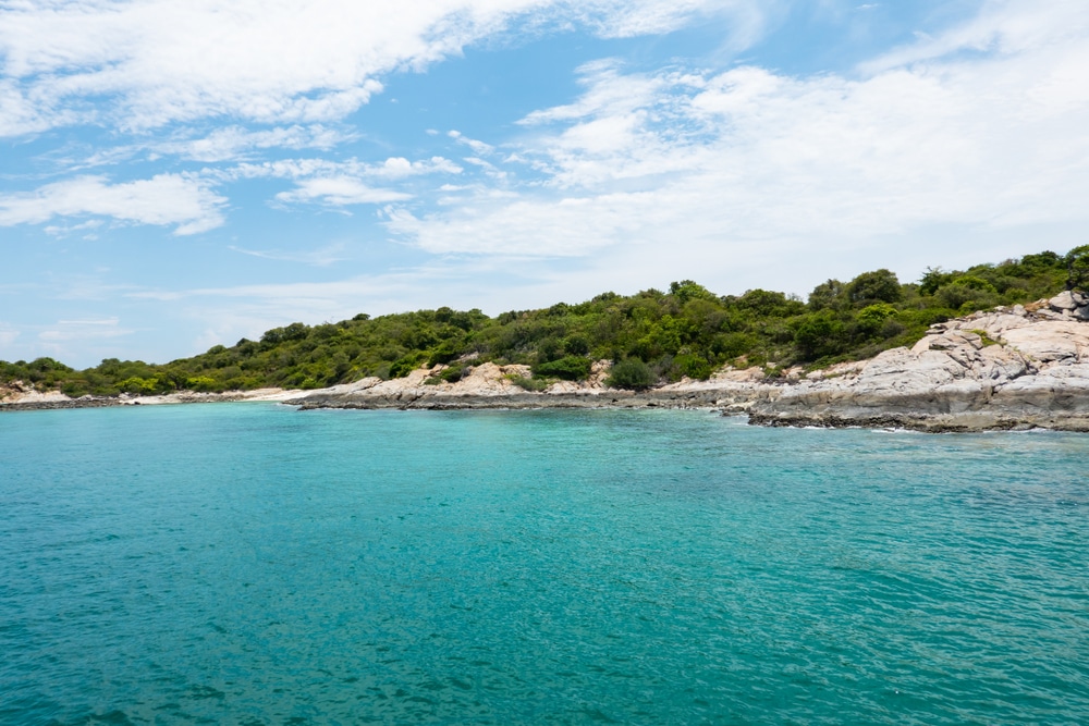 น้ำทะเลสีฟ้าใสราวกับเทอร์ควอยซ์รวม ที่เที่ยวเกาะสีชัง เกาะสวยๆ ในที่เที่ยวชลบุรี ไป เที่ยวเกาะสีชัง เดินทางง่ายๆ ใกล้กรุงเทพแบบไปเช้าเย็นกลับได้ หลีกหนีความวุ่นวาย พร้อมอวดสถานที่สโลว์ไลฟ์
ในเบื้องหน้า พร้อมชายฝั่งที่ปกคลุมไปด้วยต้นไม้และโขดหิน และท้องฟ้าที่มีเมฆบางส่วนในเบื้องหลัง—เหมาะอย่างยิ่งสำหรับการเที่ยวเกาะสีชังและสำรวจความสวยงามของเกาะสีชัง.