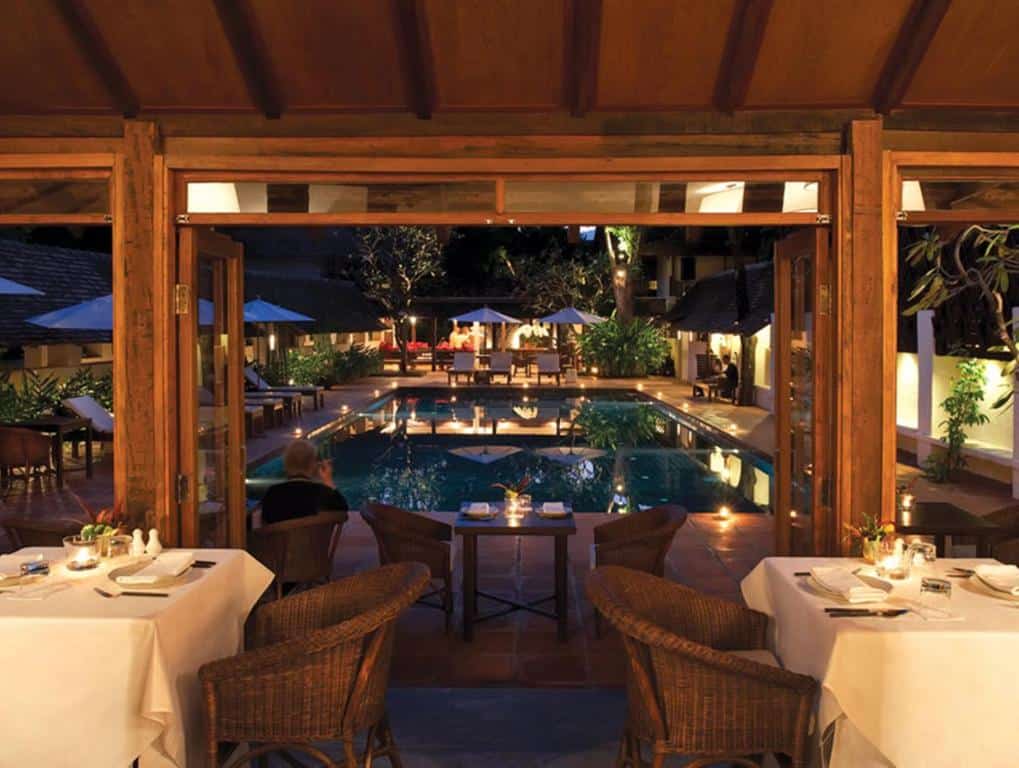 ร้านอาหารกลางแจ้งที่รีสอร์ทเชียงใหม่ พร้อมโต๊ะจัดวางอย่างเป็นระเบียบ มองเห็นสระว่ายน้ำในยามค่ำคืน รายล้อมด้วยเก้าอี้เลานจ์ ร่ม และแสงไฟบรรยากาศผ่อนคลาย.