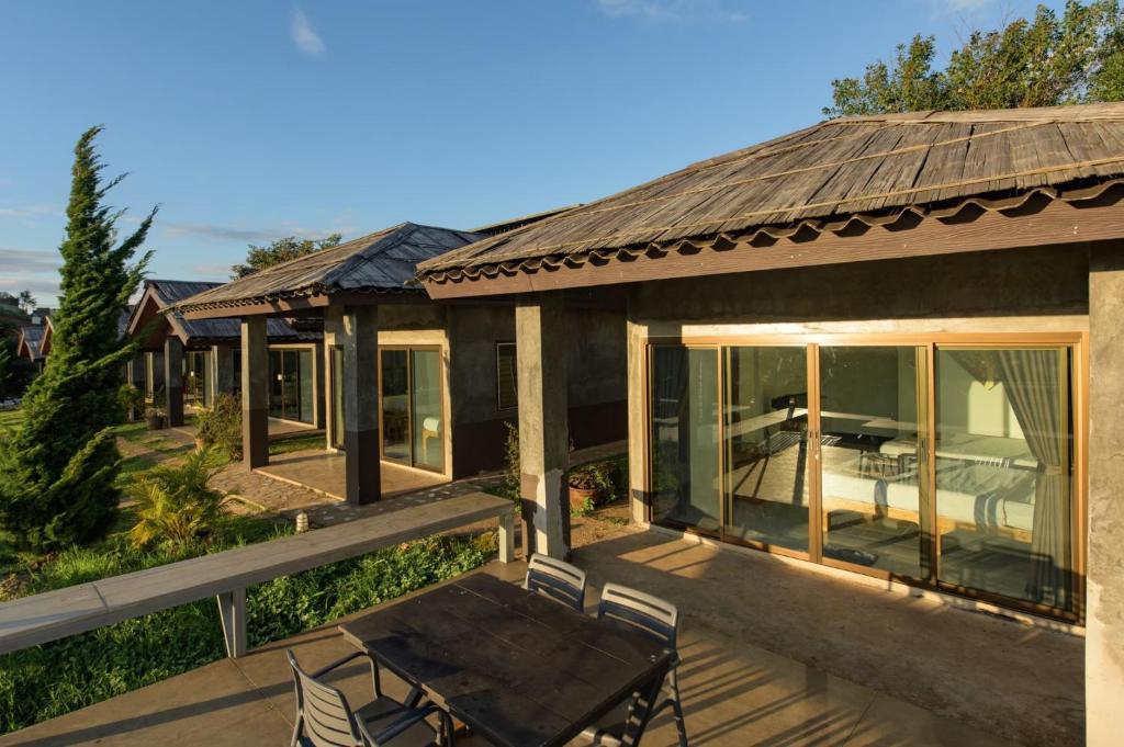 แถวของบ้านพักสไตล์โมเดิร์นพร้อมประตูบานเลื่อนกระจกขนาดใหญ่ พื้นที่นั่งเล่นกลางแจ้งบนลานระเบียง และหลังคาไม้ ตั้งอยู่ในบริเวณที่จัดแต่งภูมิทัศน์อย่างสวยงามใต้ท้องฟ้าแจ่มใส—เหมาะอย่างยิ่งสำหรับผู้ที่มองหาที่พักเชียงใหม่ที่มีเอกลักษณ์ไม่เหมือนใคร.